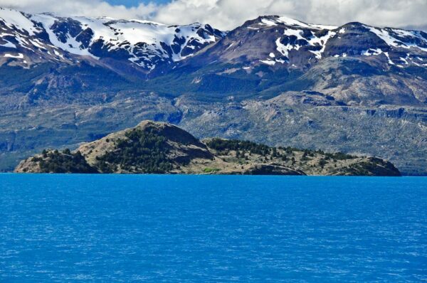 Insel vor schneebedeckten Gipfeln im Lago General Carrera, Región Aysén, Patagonien, Chile