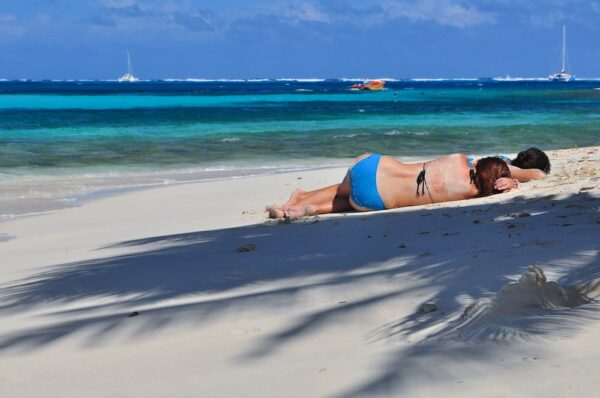 Mädchen relaxen am Strand unter Palmen, Tobago Cays, Grenadinen, Karibik