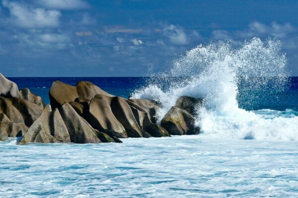 Welle bricht sich an Granitfelsen, La Digue, Seychellen