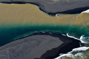 Zweifarbiger Fluss mündet ins Meer, Südküste, Island