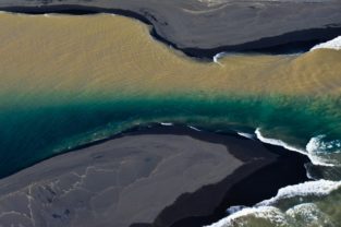 Zweifarbiger Fluss mündet ins Meer, Südküste, Island