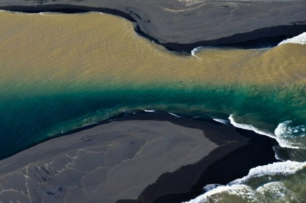 Zweifarbiger Fluss mündet ins Meer, Südküste, Island